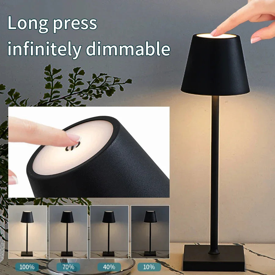 Black table lamp with dimming feature being demonstrated, surrounded by greenery.